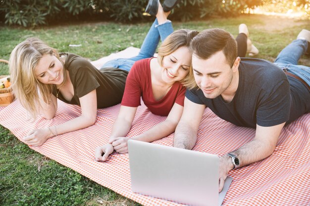 Gente que usa la computadora portátil en comida campestre