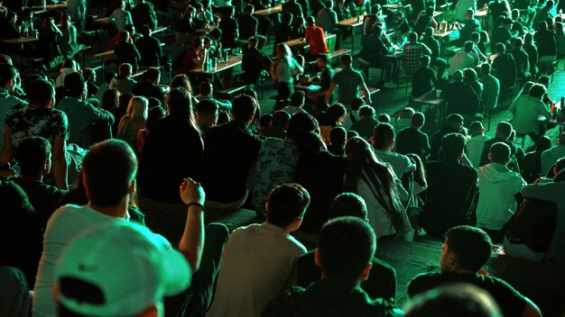 Gente sentada viendo fútbol en un lugar público por la noche