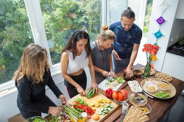 Foto gratuita gente seria cocinando verduras en la mesa de la cocina