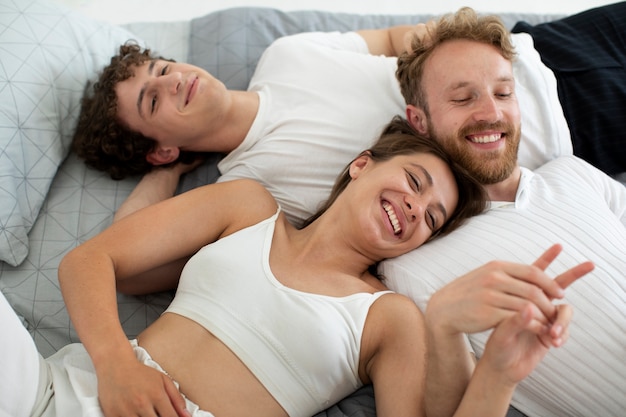 Foto gratuita gente sonriente de alto ángulo acostada en la cama