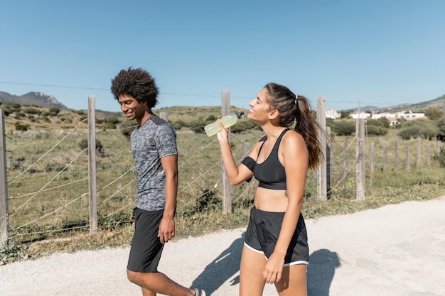 Gente sonriente caminando mientras la mujer bebe agua