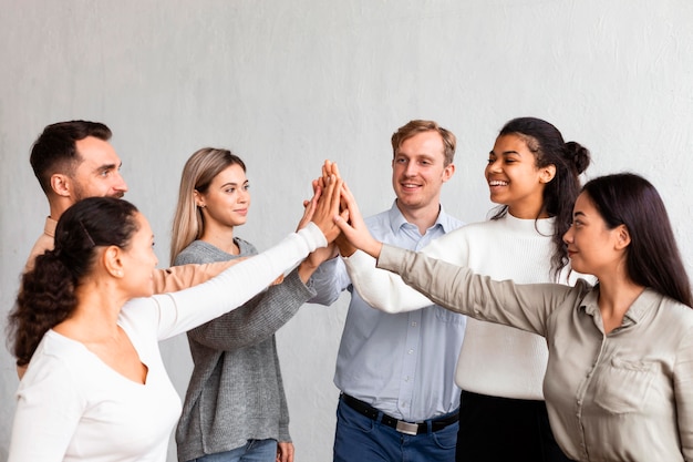 Foto gratuita gente sonriente chocando los cinco en una sesión de terapia de grupo