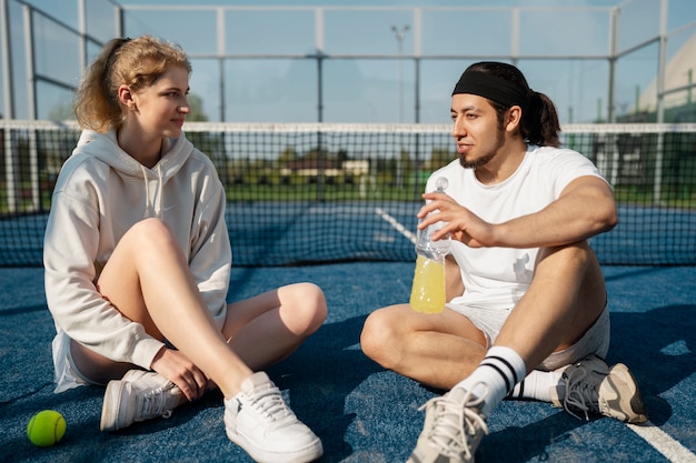 Gente sonriente sentada al aire libre con bebidas full shot