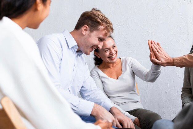 Gente sonriente en una sesión de terapia de grupo chocando los cinco