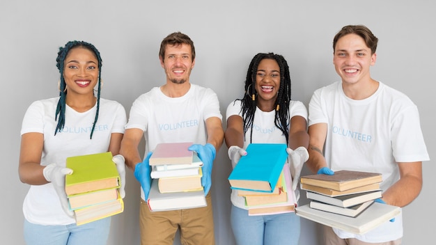 Gente sonriente sosteniendo un montón de libros para donarlos