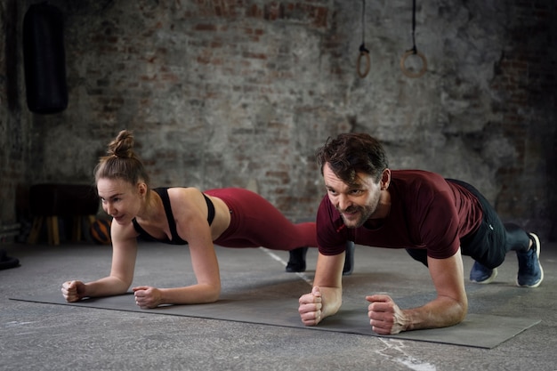 Gente sonriente de tiro completo entrenando en colchoneta de yoga