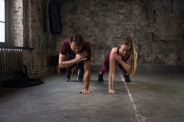 Gente sonriente de tiro completo haciendo burpees juntos