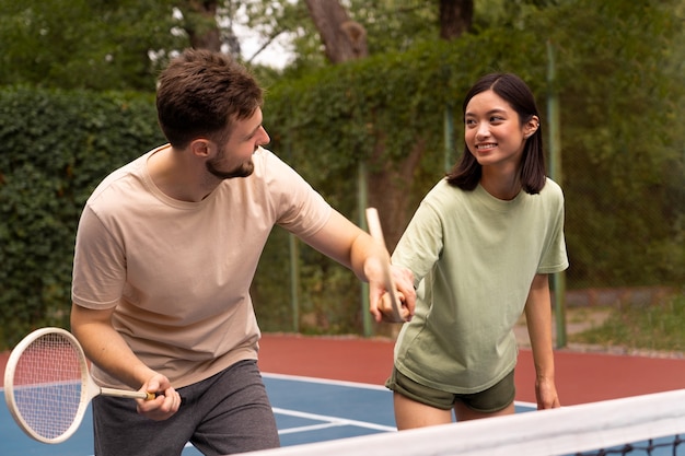 Gente sonriente de tiro medio en el campo de bádminton