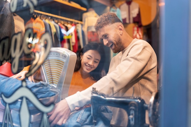 Foto gratuita gente sonriente de tiro medio en la tienda de segunda mano