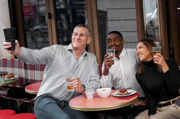 Gente sonriente tomando selfie en bistro plano medio