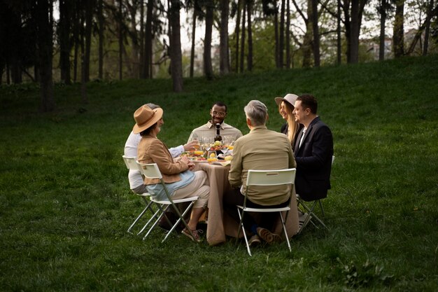 Gente de tiro completo comiendo en la naturaleza.