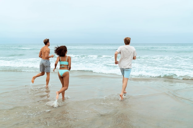 Foto gratuita gente de tiro completo corriendo en la playa