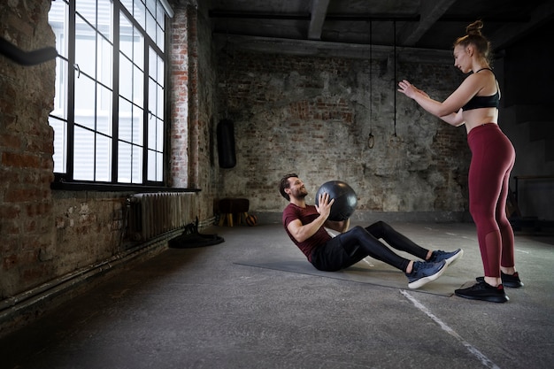 Gente de tiro completo entrenando con pelota y colchoneta de yoga.