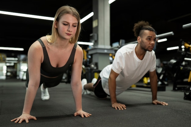 Gente de tiro completo haciendo burpees en el gimnasio juntos