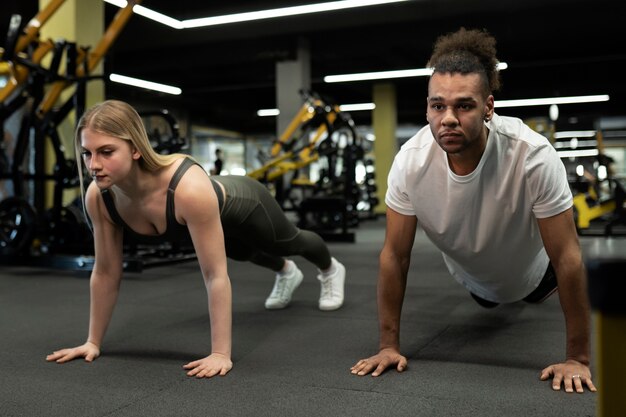 Gente de tiro completo haciendo burpees en el gimnasio