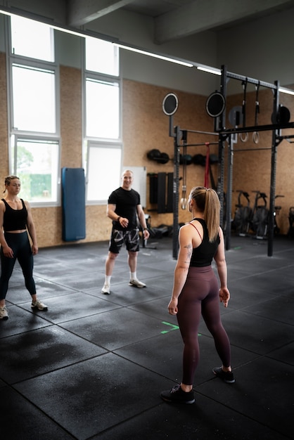 Gente de tiro completo haciendo burpees en el gimnasio