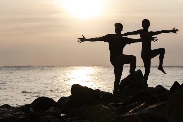 Gente de tiro completo haciendo yoga al atardecer