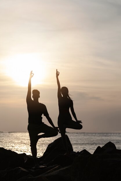 Gente de tiro completo haciendo yoga juntos al atardecer