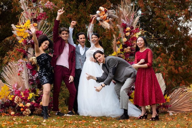 Gente de tiro completo posando en la boda