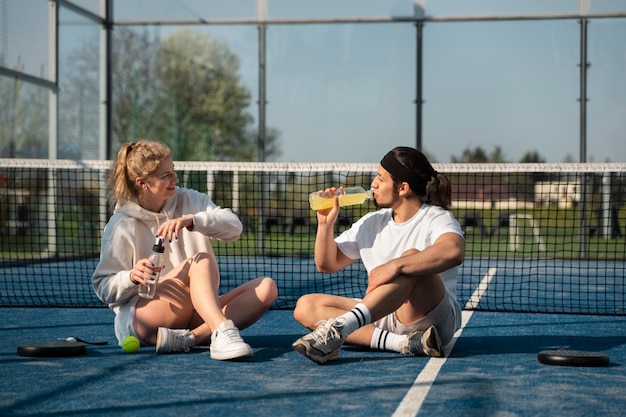 Gente de tiro completo sentada al aire libre con bebidas