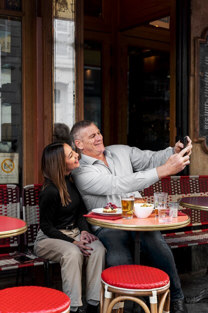 Gente de tiro completo tomando selfie en bistro