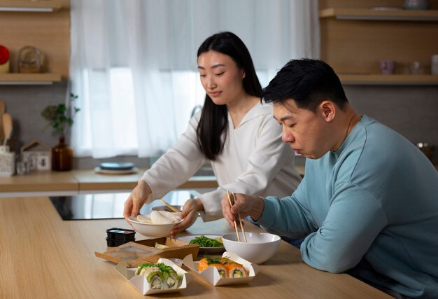 Gente de tiro medio comiendo comida asiática.