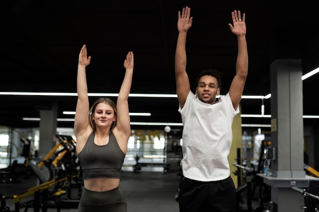 Gente de tiro medio haciendo burpees en el gimnasio