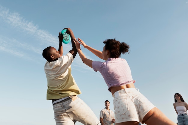 Gente de tiro medio jugando en la playa de ángulo bajo