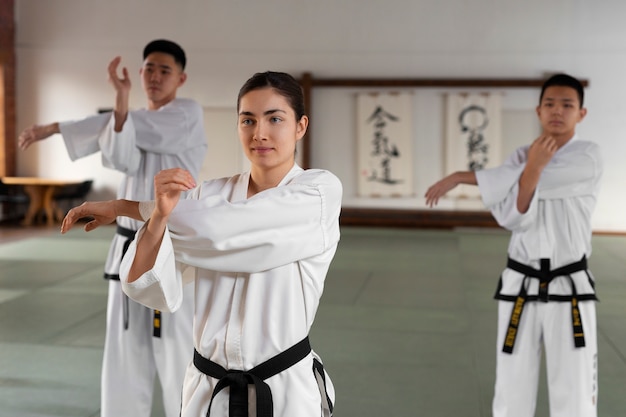 Gente de tiro medio practicando taekwondo.