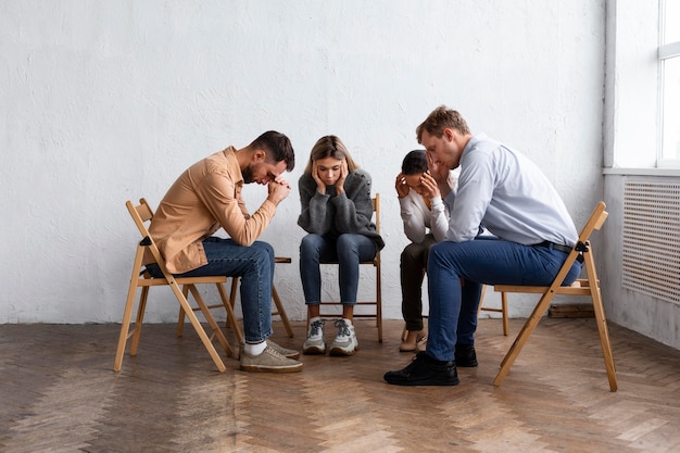 Foto gratuita gente triste en sillas en una sesión de terapia de grupo