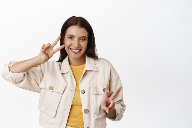 Foto gratuita gente de verano. hermosa mujer adulta feliz, mostrando signos de paz, dientes blancos sonrientes y mirando positivamente a la cámara, disfrutando del tiempo libre, fondo blanco