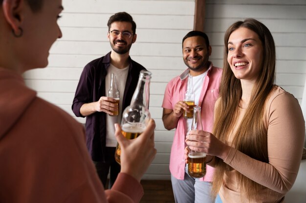 Foto gratuita gente vitoreando y bebiendo cerveza mientras juegan al beer pong en una fiesta interior