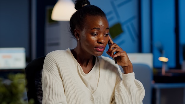 Gerente africano nervioso discutiendo en el teléfono inteligente con el empleado