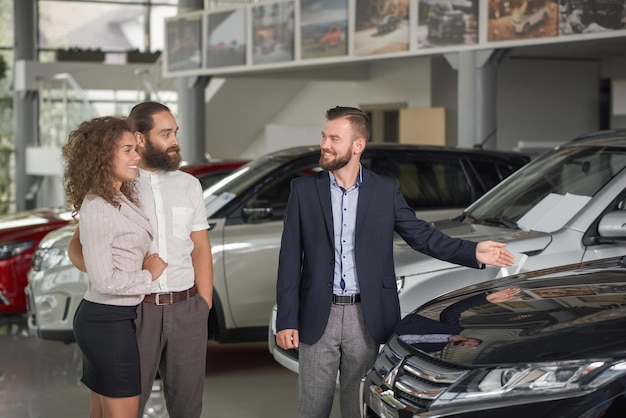 Gerente del centro de automóviles que muestra el automóvil a los clientes