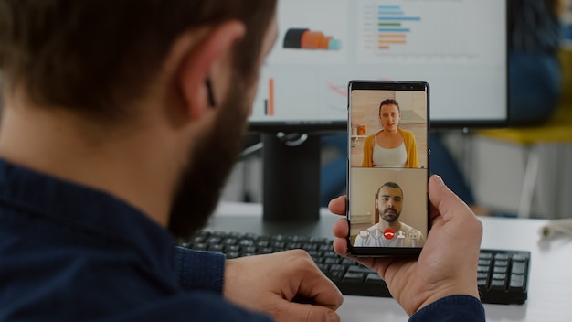 Gerente discapacitado hablando por videollamada con amigos con smartphone tomando un descanso durante el tiempo de trabajo