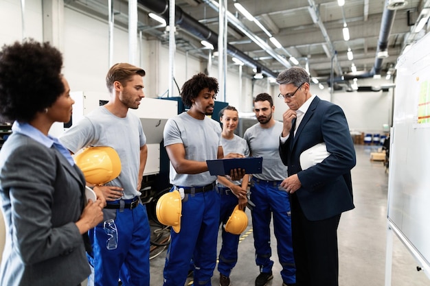 El gerente de la empresa y el trabajador afroamericano cooperan mientras analizan los planes de producción en una reunión en una fábrica