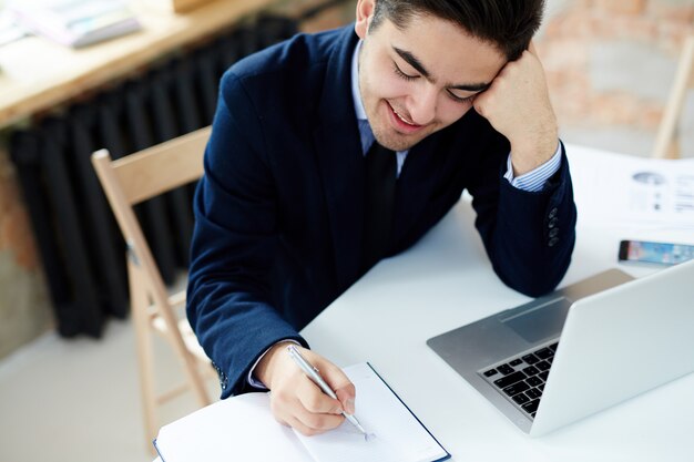 Gerente escribiendo en el cuaderno diario