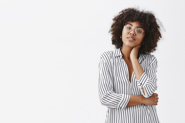 Gerente femenina moderna, guapa y elegante con blusa a rayas tocando el cuello y la cabeza inclinada, lo que hace que el masaje se sienta cansado de estar sentado y trabajar todo el día