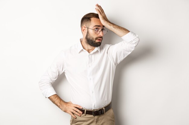 El gerente del hombre molesto pone los ojos en blanco y se golpea la frente, la palma de la mano por algo cansado, de pie