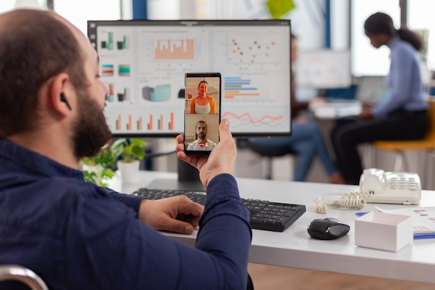 Gerente inválido discapacitado hablando por videollamada con amigos con smartphone tomando un descanso durante el tiempo de trabajo