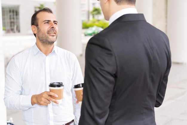 Gerente de mediados de adulto confidente que habla con el ejecutivo en el descanso para tomar café