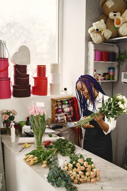 Gerente de mujer de pie en el lugar de trabajo. Señora con planta en manos. Flores de corte famale. Concepto de floristería.