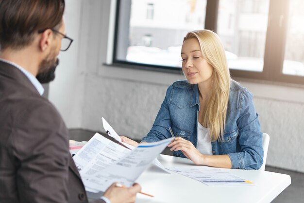 Gerente mujer rubia feliz tiene conversación con colega masculino