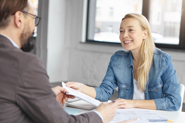 Gerente mujer rubia feliz tiene conversación con colega masculino