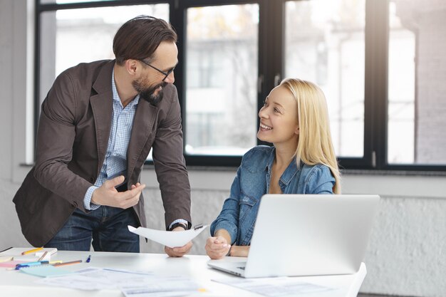 Gerente mujer rubia feliz tiene conversación con colega masculino