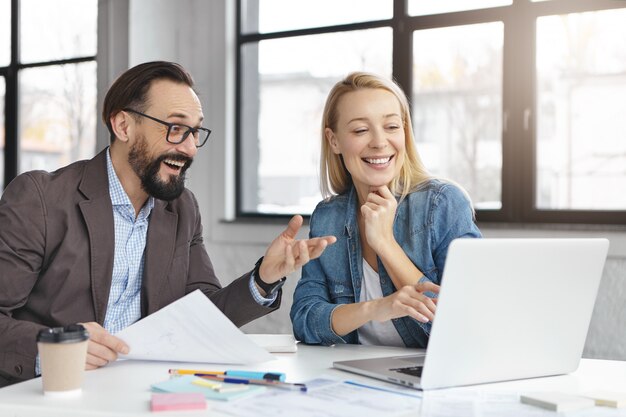 Gerente mujer rubia feliz tiene conversación con colega masculino