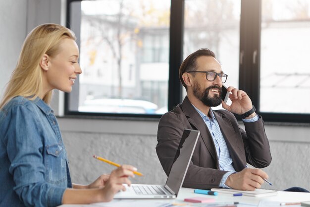 Gerente mujer rubia feliz tiene conversación con colega masculino