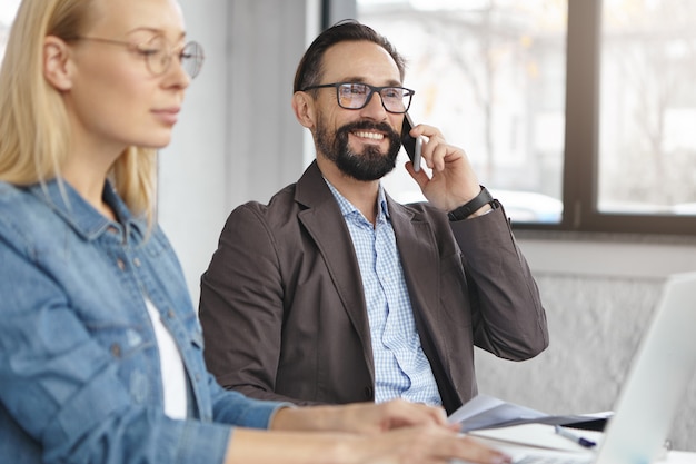 Gerente mujer rubia feliz tiene conversación con colega masculino