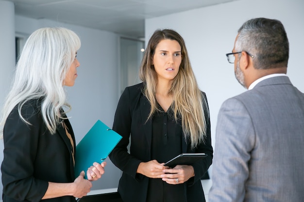 Gerente mujer seriamente preocupada con tableta informando al CEO de la empresa. Tiro medio. Concepto de comunicación empresarial