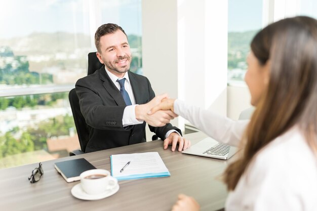 Gerente de recursos humanos sonriente felicitando al candidato por una entrevista de trabajo exitosa